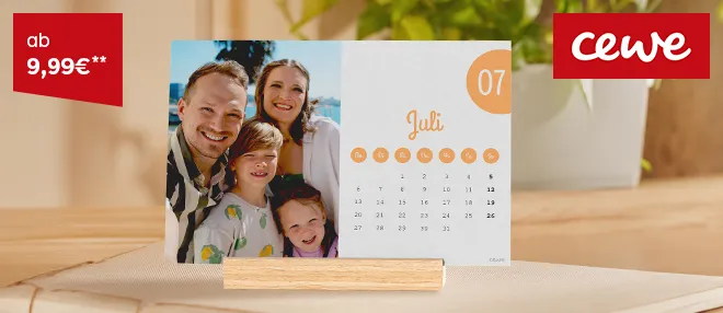 Fotokalender als stilvolle Wanddeko Ein Kalender mit winterlichem Foto hängt an einer Wand, umgeben von natürlicher Dekoration.