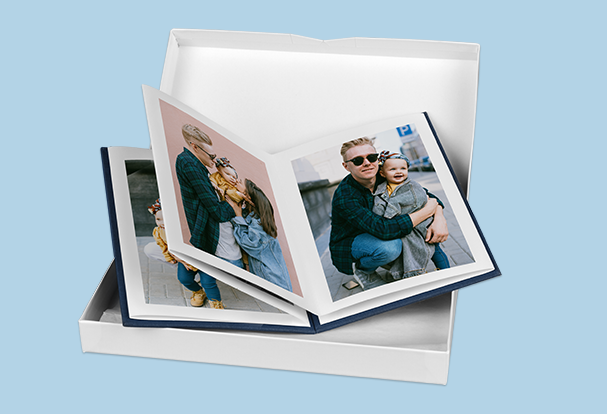 Leporello mit 10 Fotos als personalisiertes Babygeschenk Ein geöffnetes myLeporello Buch mit Vater-Kind-Fotos inkl. einer weißen Geschenkbox, ideal als personalisiertes Babygeschenk.