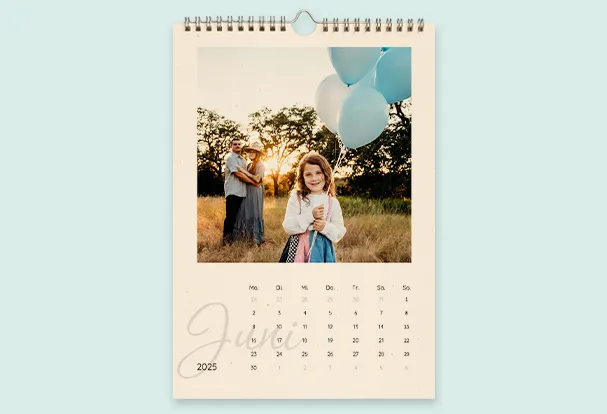 personalisierter Wandkalender aus Recyclingpapier Personalisierter Wandkalender mit Spiralbindung, der ein Familienfoto und Monatsübersicht mit dekorativer Gestaltung zeigt.
