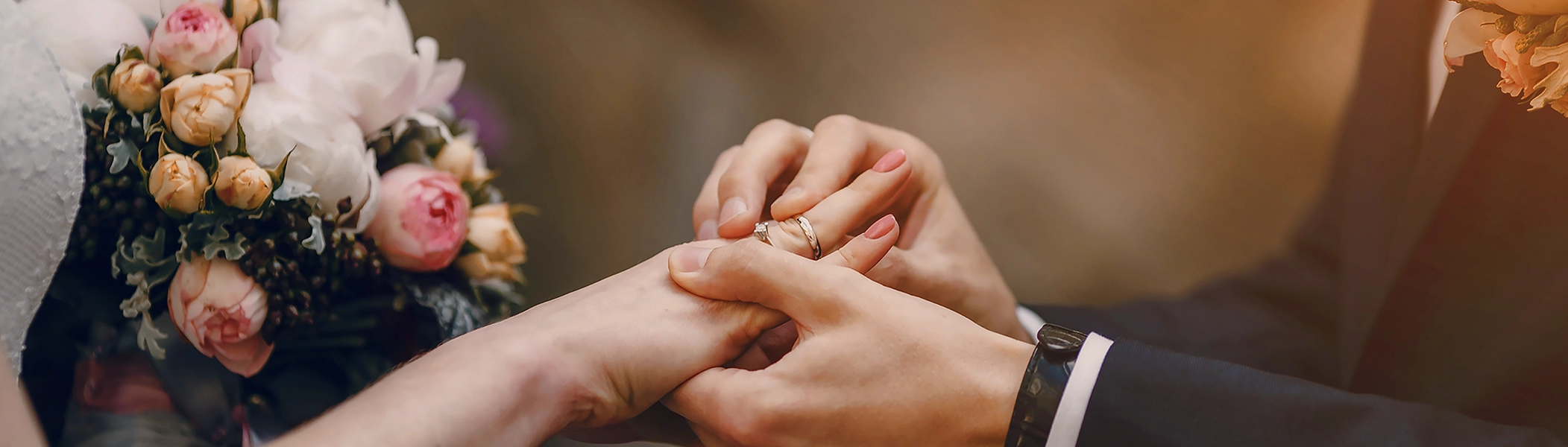 Inspiration für personalisierte Hochzeitsgeschenke Brautstrauß und Hände eines Paares beim Anstecken des Rings. Entdeckt Geschenkideen zur Hochzeit in der ROSSMANN Fotowelt!