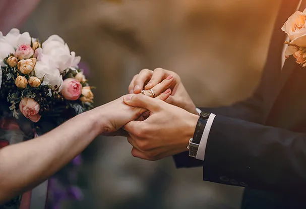 Foto-Geschenkideen: ROSSMANN Hochzeitswelt Ein paar Hände steckt einem anderen einen Ehering an. In der Hochzeitswelt findet ihr personalisierte Foto-Geschenke zur Hochzeit.