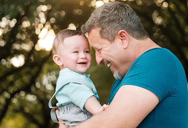 Willkommen in der liebevoll gestalteten Babywelt Ein lächelnder Papa mit Baby – ein Motiv aus der Babywelt, in der ihr personalisierte Geschenke zur Geburt entdecken könnt.
