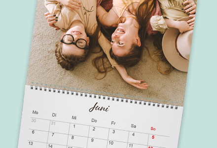 Ein Foto-Kalender, auf der eine Mutter und ein lachendes Kind mit großer Brille auf dem Boden liegen.