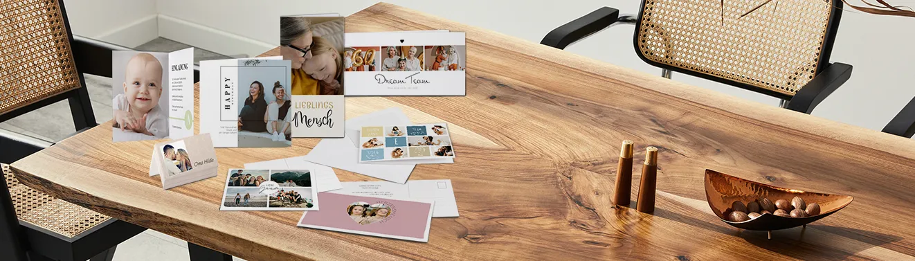 Klapp- und Echtfotokarte beidseitig gestaltbar, einzeln und als 10er-Set Verschiedene personalisierte Grußkarten mit Familienmotiven auf einem hellen Holztisch. Gestaltet hier Karten mit euren Fotos!