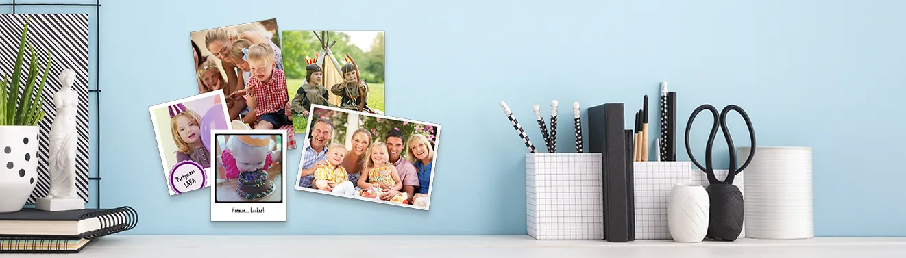 Fotoabzüge drucken – persönliche Familienfotos stilvoll als Wanddekoration präsentieren Mehrere Fotoabzüge mit Familien- und Kinderfotos als persönliche Wanddekoration an einer hellblauen Wand arrangiert